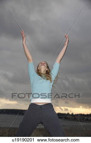 Woman stretching out arms in front of dark clouds, low angle view View Large Photo Image Stock Image - Woman stretching out arms in front of dark clouds, low angle view. Fotosearch