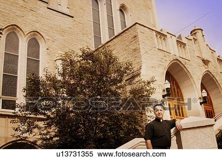 Stock Photography - A priest standing outside the church. Fotosearch