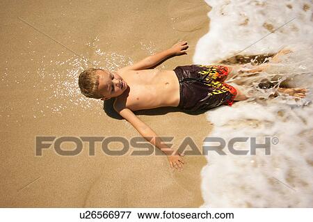Boy lying on beach in water View Large Photo Image Stock Photo - Boy lying on beach in water. Fotosearch