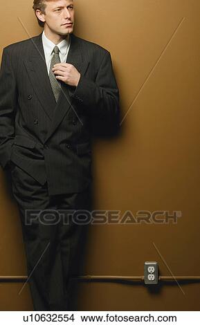 Picture - Businessman leaning on interior wall. Fotosearch