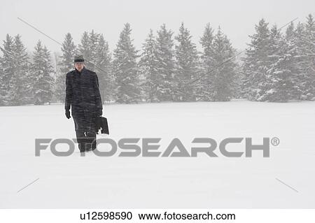 Stock Image - Businessman walking in the snow. Fotosearch