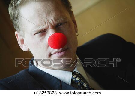 Stock Image - Businessman wearing red nose. Fotosearch