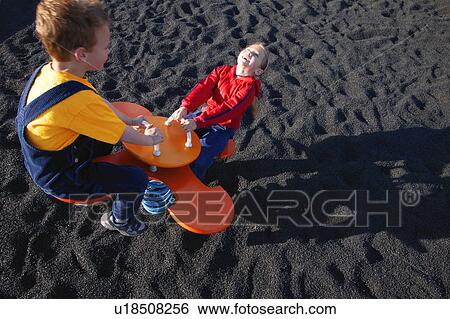 Stock Photograph - Children on see-saw at the park. Fotosearch