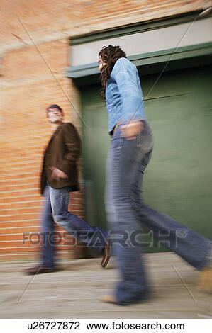 Stock Image - Couple walking on pavement. Fotosearch