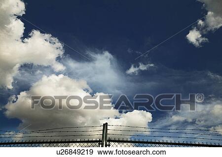 Dark sky behind chain link and barbed wire fence View Large Photo Image Stock Photo - Dark sky behind chain link and barbed wire fence. Fotosearch