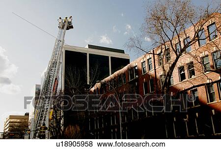 Stock Photo - Firefighters outside a large building. Fotosearch