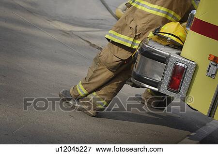 Stock Photo - Firemen leaning against fire truck. Fotosearch