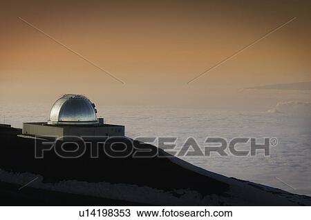 Stock Image - Hawaiian telescope looking over clouded landscape below. Fotosearch