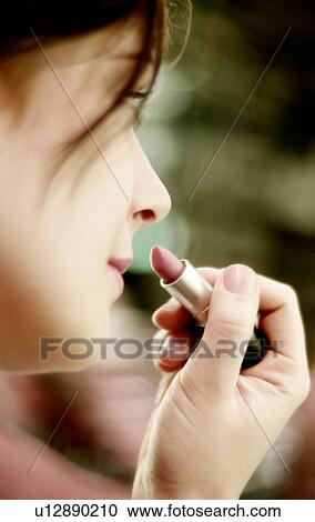 Stock Image - Lady applying lipstick. Fotosearch