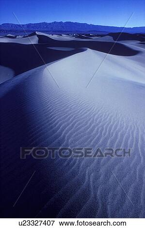 Large sand dunes in desert with mountains in background View Large Photo Image Stock Photo - Large sand dunes in desert with mountains in background. Fotosearch