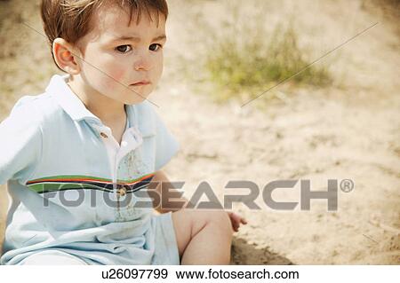 Stock Photo - Little boy sitting on the sand. Fotosearch