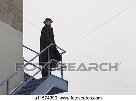Stock Image - Lone man standing on an outdoor staircase. Fotosearch