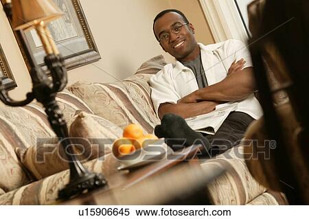 Stock Photography - Man relaxing on sofa. Fotosearch