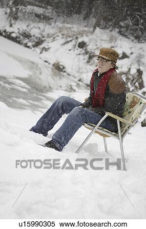 Stock Photography - Man sitting on chair in snow. Fotosearch