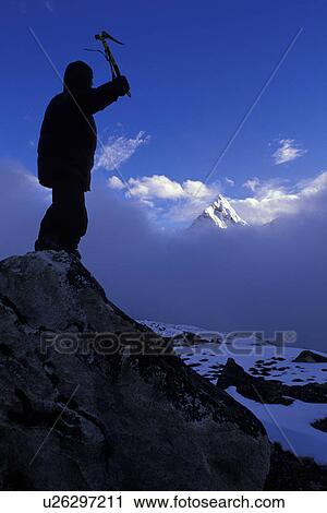 Mountaineer on peak with mountain peak rising out of clouds in background View Large Photo Image Stock Image - Mountaineer on peak with mountain peak rising out of clouds in background. Fotosearch