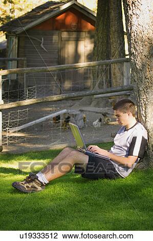 Stock Image - Teen working on computer outside. Fotosearch