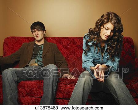 Stock Photo - Trendy young couple sitting on sofa. Fotosearch