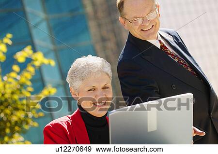 Two business people looking at a laptop View Large Photo Image Stock Photo - Two business people looking at a laptop. Fotosearch