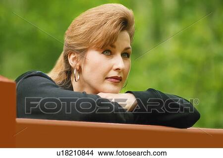 Woman deep in thought leaning on gate View Large Photo Image Picture - Woman deep in thought leaning on gate. Fotosearch