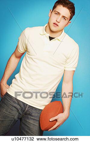 Stock Image - Young man holding football. Fotosearch