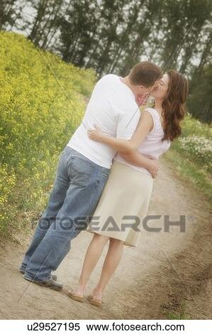 Stock Photography - A couple kiss tenderly on a path. Fotosearch
