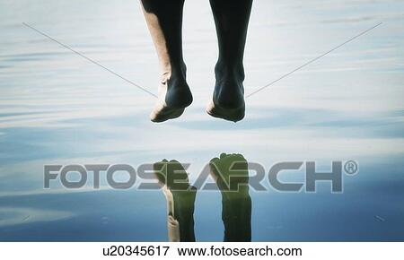 Stock Photo - A pair of feet dangling over the water. Fotosearch