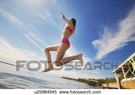 A teenage girl jumping into a lake View Large Photo Image Stock Photography - A teenage girl jumping into a lake. Fotosearch