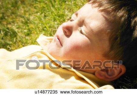 Stock Photography - A young boy lying in the sun. Fotosearch