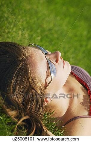 A young woman sunbathes on the grass View Large Photo Image Stock Image - A young woman sunbathes on the grass. Fotosearch