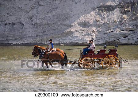 Stock Photo - Cowboys and buggy crossing a river. Fotosearch