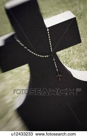 Stock Image - Rosary draped over a gravestone. Fotosearch