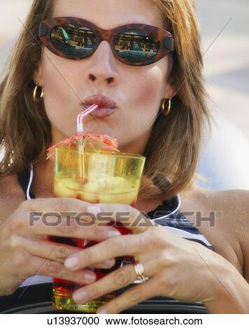 Stock Image - Woman drinks a refreshing beverage. Fotosearch