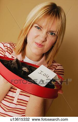 Stock Image - A teenage girl upset over an empty box of chocolates. Fotosearch