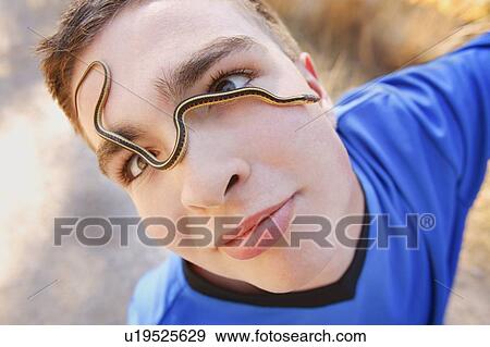 Stock Photo - Boy with snake on his face. Fotosearch