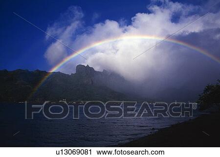 Stock Image - Rainbow and fog over Cooks Bay, French Polynesia. Fotosearch
