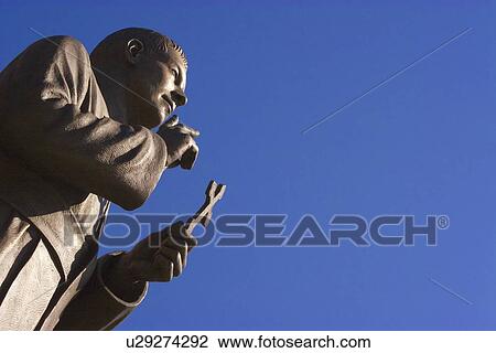 Stock Image - Statue holding cross. Fotosearch