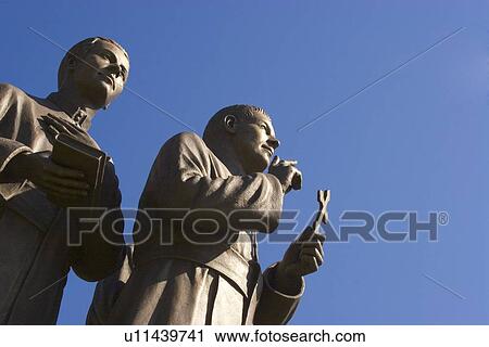 Stock Image - Statue of two men holding cross and book. Fotosearch