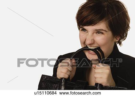 Picture - Woman chewing on purse handle. Fotosearch