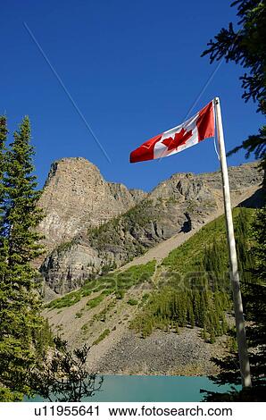 Stock Image - Canadian flag with mountains in background. Fotosearch