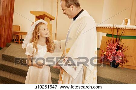 Stock Photo - Child receives certificate from Priest. Fotosearch