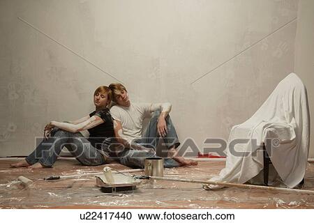 Stock Image - Couple rests after a hard day of painting. Fotosearch