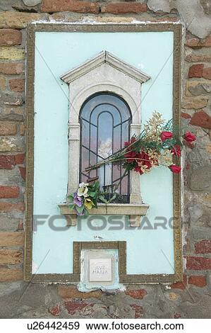Stock Photo - Madonna shrine with floral offerings. Fotosearch