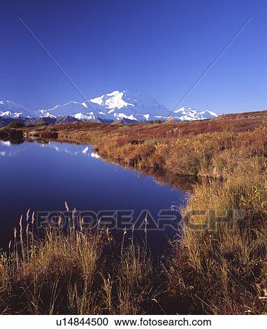 Stock Image - Pond by snow capped mountains. Fotosearch
