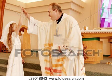 Priest celebrates with girl on first communion View Large Photo Image Stock Image - Priest celebrates with girl on first communion. Fotosearch