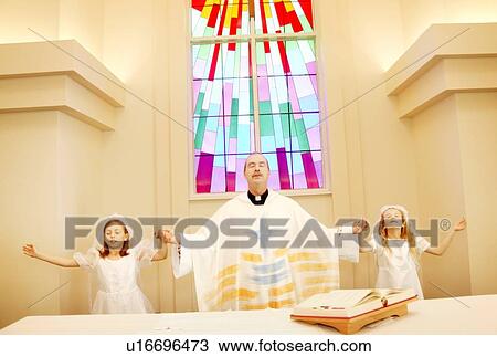 Stock Image - Priest with girls on first communion. Fotosearch