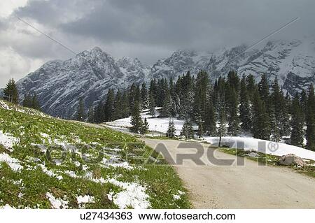 Stock Image - Snow covering alpine landscape and winding road. Fotosearch