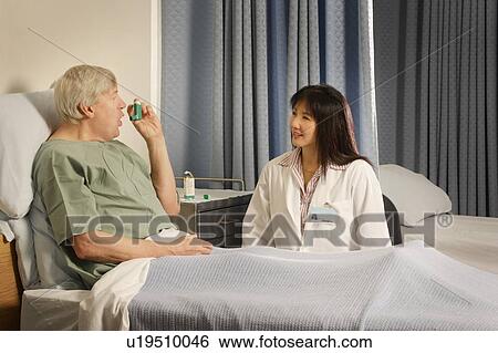 Stock Photograph - A health care professional supervises patient using inhaler. Fotosearch