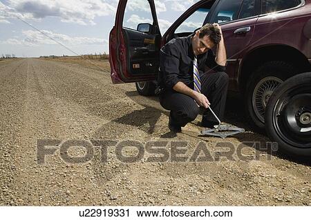 A man struggle with changing tire View Large Photo Image Stock Image - A man struggle with changing tire. Fotosearch