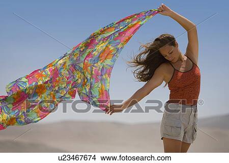 Picture - A woman holds out a scarf in the wind. Fotosearch