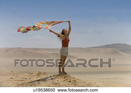 A woman holds up a scarf to the desert wind View Large Photo Image Stock Image - A woman holds up a scarf to the desert wind. Fotosearch